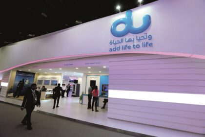 Trade show booth featuring a large blue 'du' logo and the slogan 'add life to life' on a curved purple wall, with attendees walking nearby. - برفيلكس - brieflex
