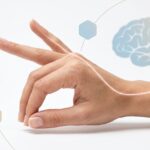 Outstretched hand with a glowing curved line linking to a brain illustration, symbolizing neural connection and touch.
